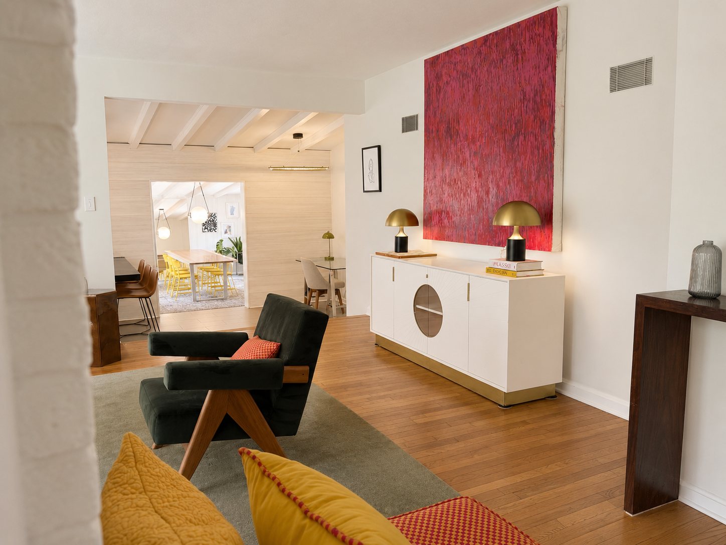 Living room with green lounge chairs and sideboard, open to the dining room beyond